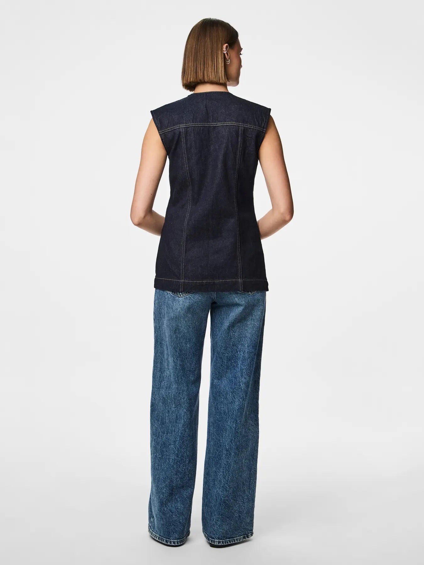 ryggen af model med mørkeblå denimvest med v-hals og knaplukning foran. PIECES PCNUA Denimvest Indigo