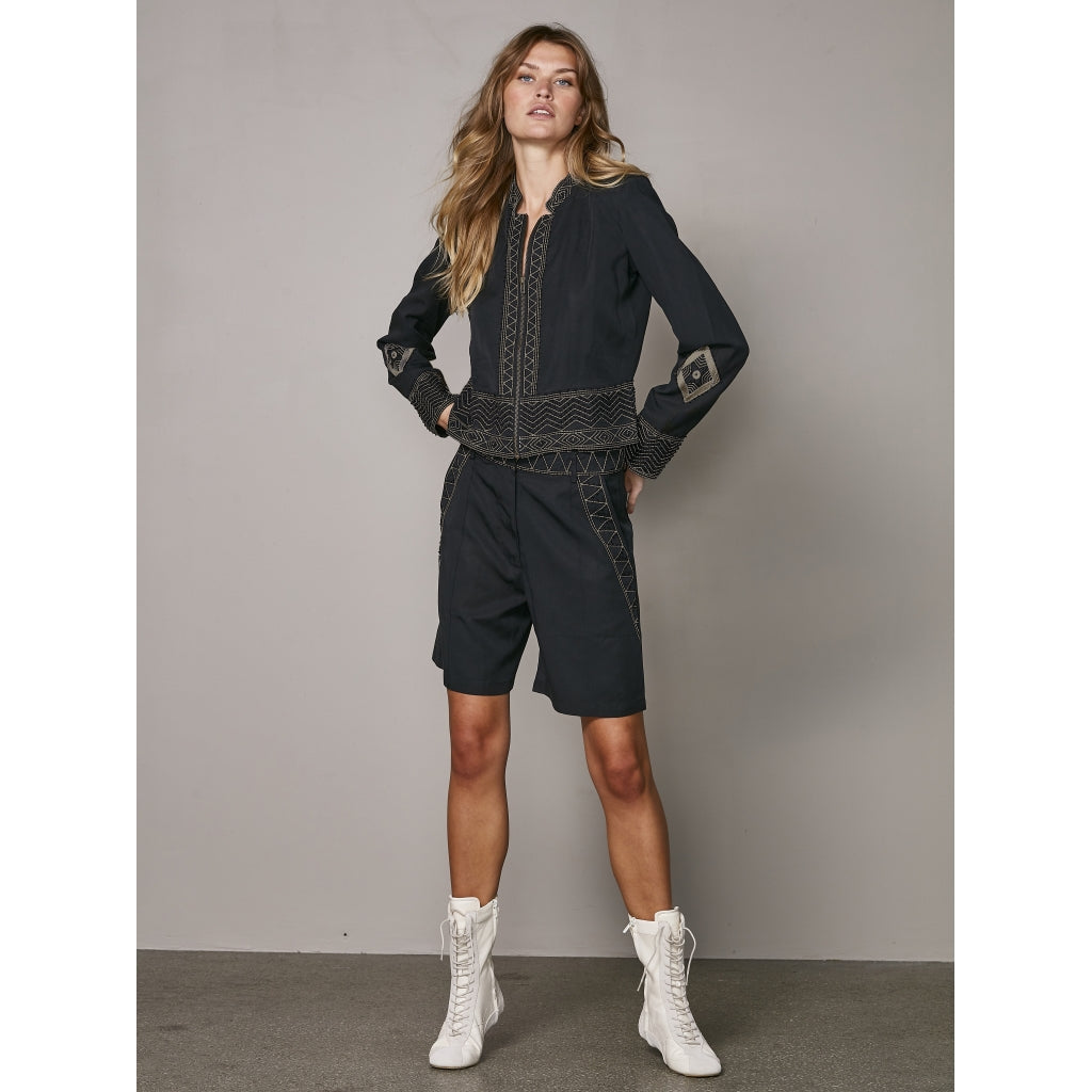 model med sorte shorts med broderidetaljer. NÜ Zanna Shorts Black og matchende jakke