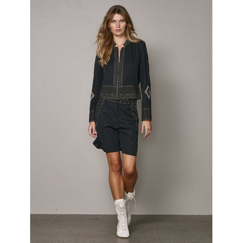 model med kort sort jakke med broderidetaljer og lynlåslukning. NÜ Zanna Jacket Black