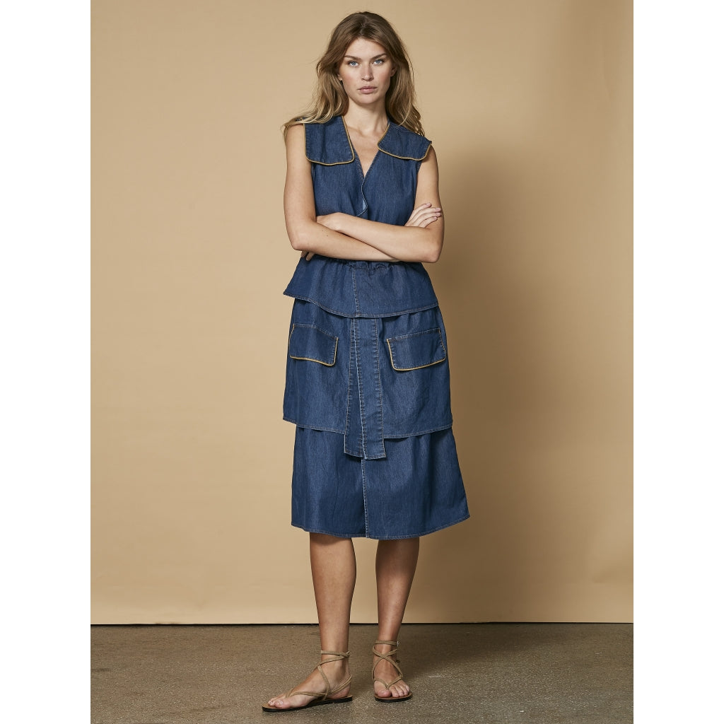 model med ærmeløs blå denimkjole med skørt i flere lag. NÜ Ziga denimkjole