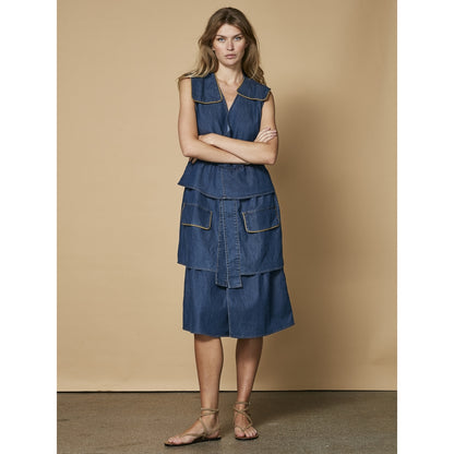 model med ærmeløs blå denimkjole med skørt i flere lag. NÜ Ziga denimkjole