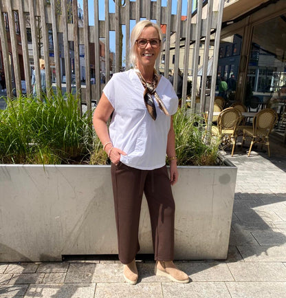 Lene med hvid t-shirt og brune bukser