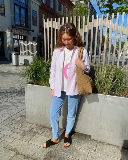 Luna i lyserød stribet skjorte åben over en t-shirt til et par jeans