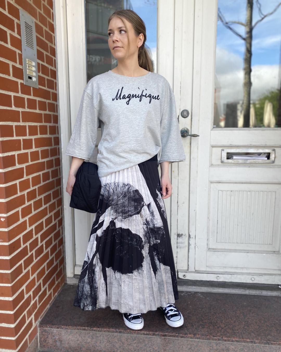 Marie i grå t-shirt og mønstret sort hvid nederdel