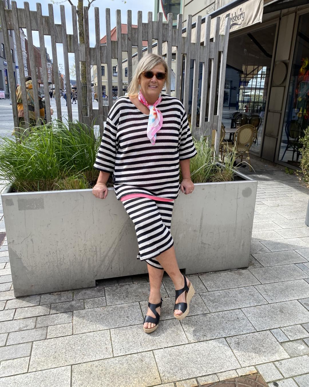 Janni med lyserødt tørklæde og stribet t-shirt og stribet korte bukser