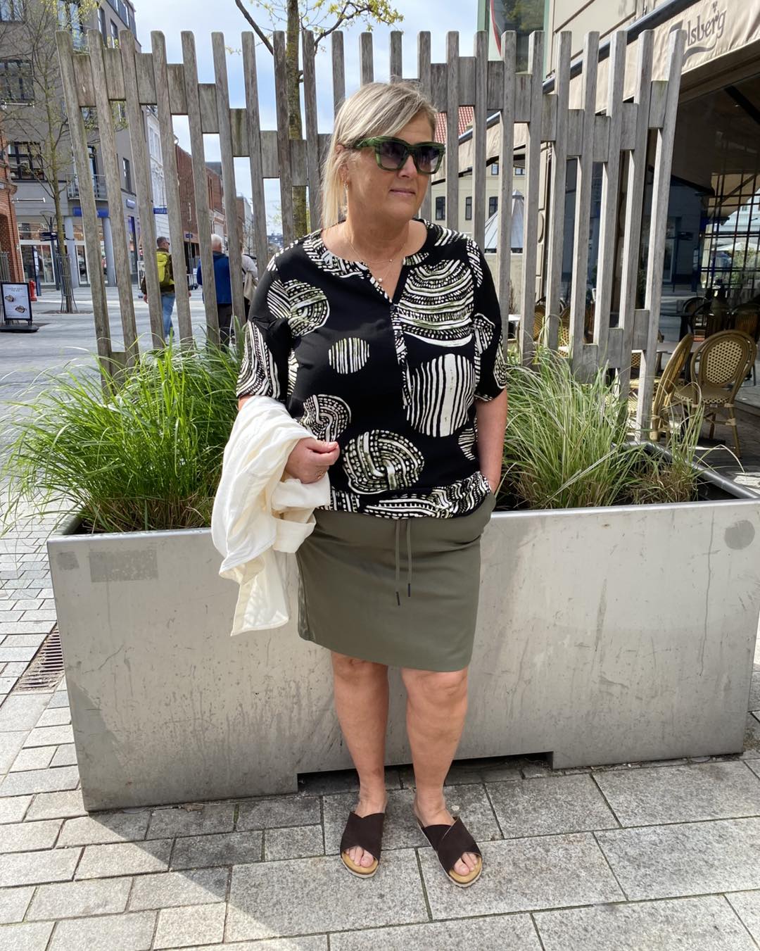 Janni med mønstret bluse og kort grøn nederdel med elastik og snøre i taljen