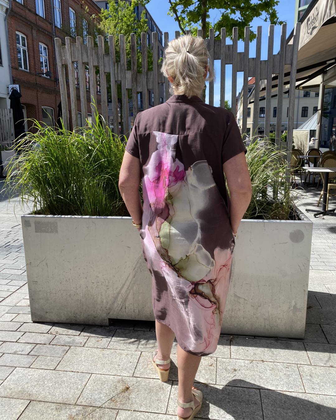 ryggen af Lene i mønstret kjole i røde nuancer fra Nü