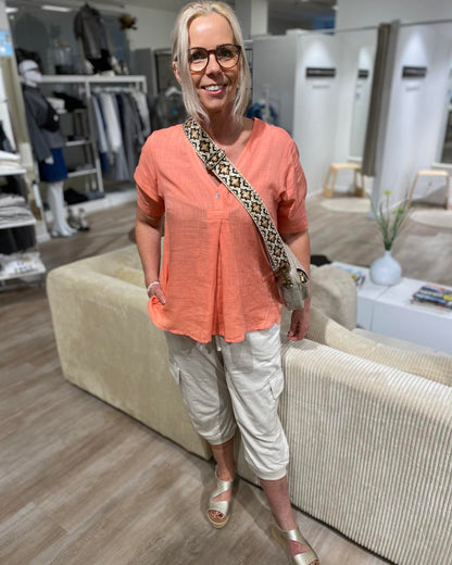 Lene med coralfarvet t-shirt og beige capribukser