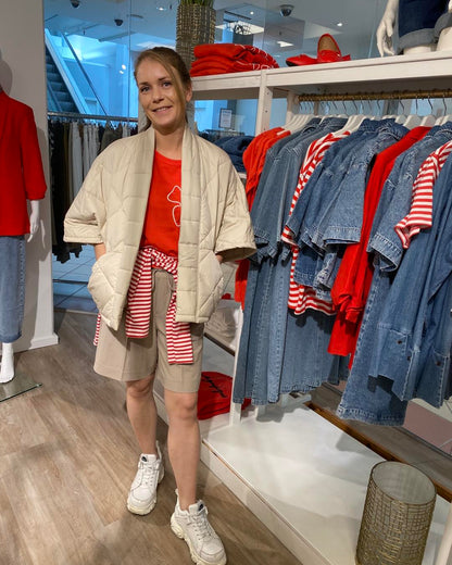 marie med rød t-shirt, beige vest og shorts