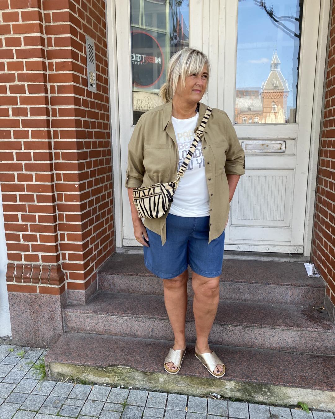 janni med åben grøn hørskjorte, hvid t-shirt og denimshorts