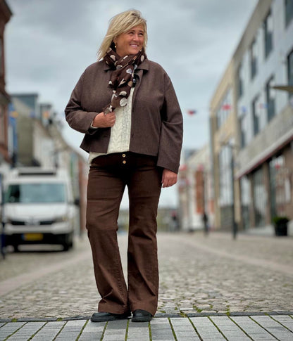 Janni med brun jakke, hvid strik og brune bukser og brunt tørklæde