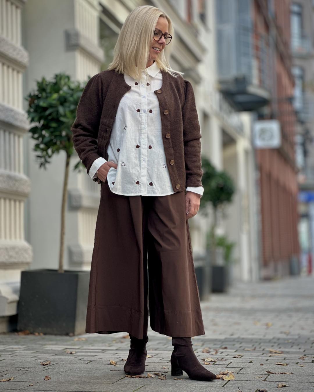 Lene med brun cardigan, hvid skjorte med hjerter og brune bukser