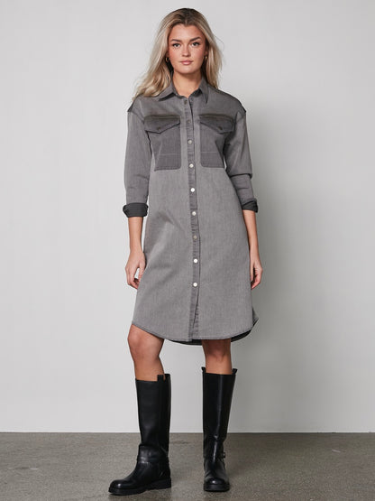 model foran med grå kjole med denim-llok, lange ærmer, knappelukning og to store brystlommer. NÜ Yelena Dress Grey 8300-23