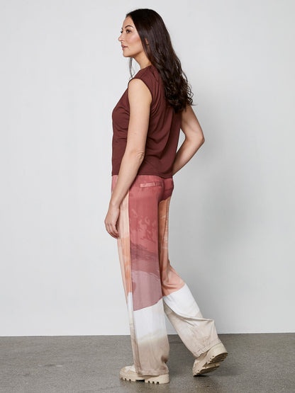 model fra siden med mønstrede bukser i røde og lyse nuancer med sidelommer og elastik i taljen. NÜ Elina Yola Trousers Berry Red Mix 8306-10