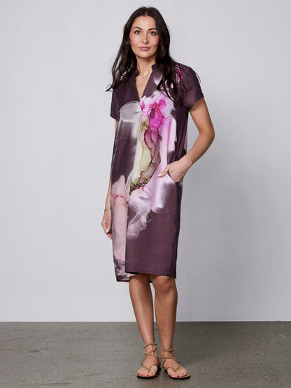 model med hånden i lomme på kortærmet kjole med print og løs pasform. NÜ Zoya kjole Grape Mix