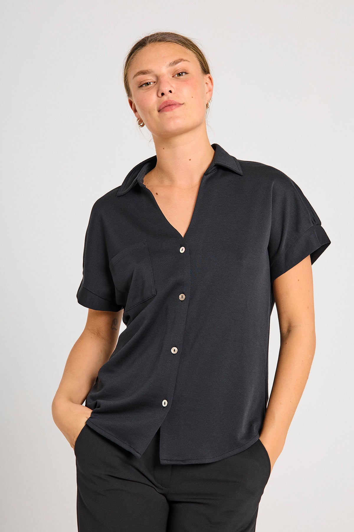 model med kortærmet sort skjorte t-shirt med knappelukning og brystlomme. Freequent Black FQRUE-BLOUSE