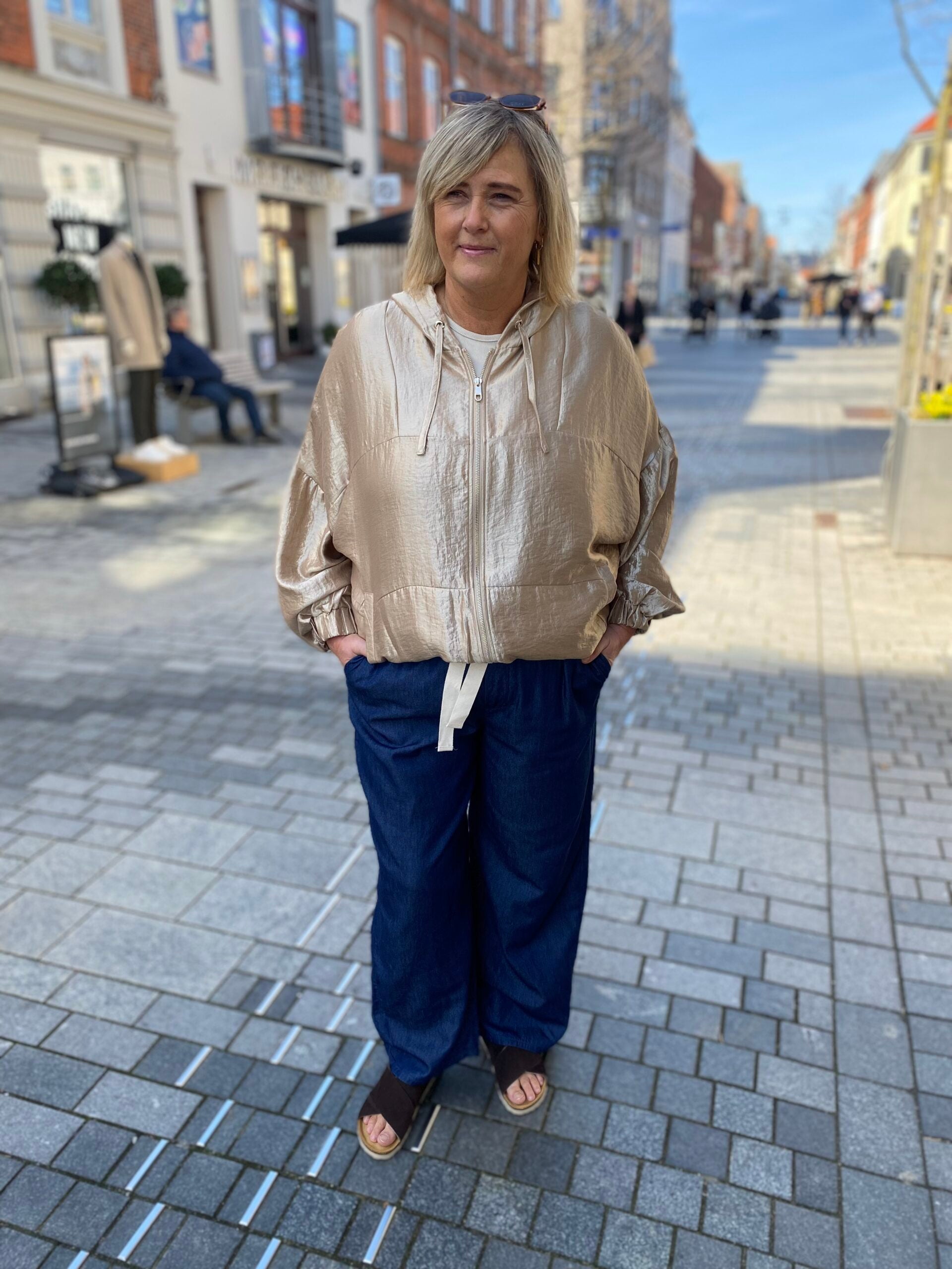 Janni med jeans og en kort jakke i guld. ONLY Carmakoma CARGRACE Bomber jacket
