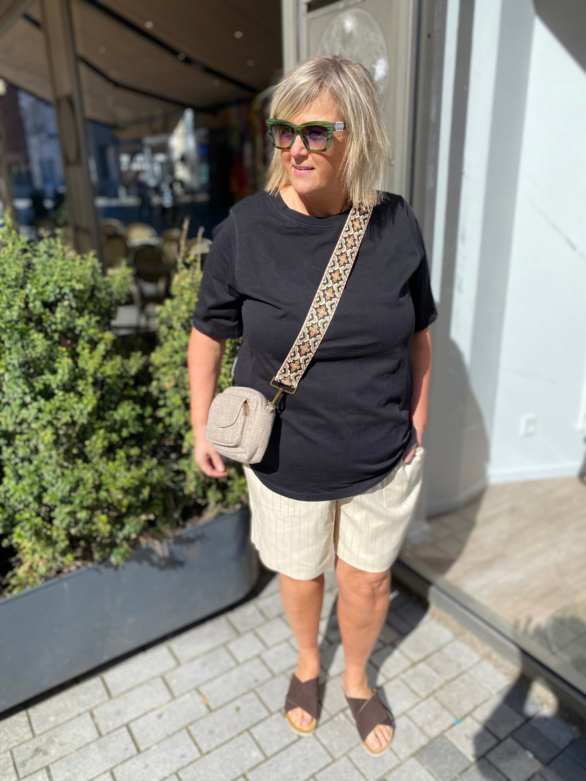 Janni med sort t-shirt og beige shorts med tynde sorte striber. ONLY Carmakoma CARMONICA Shorts