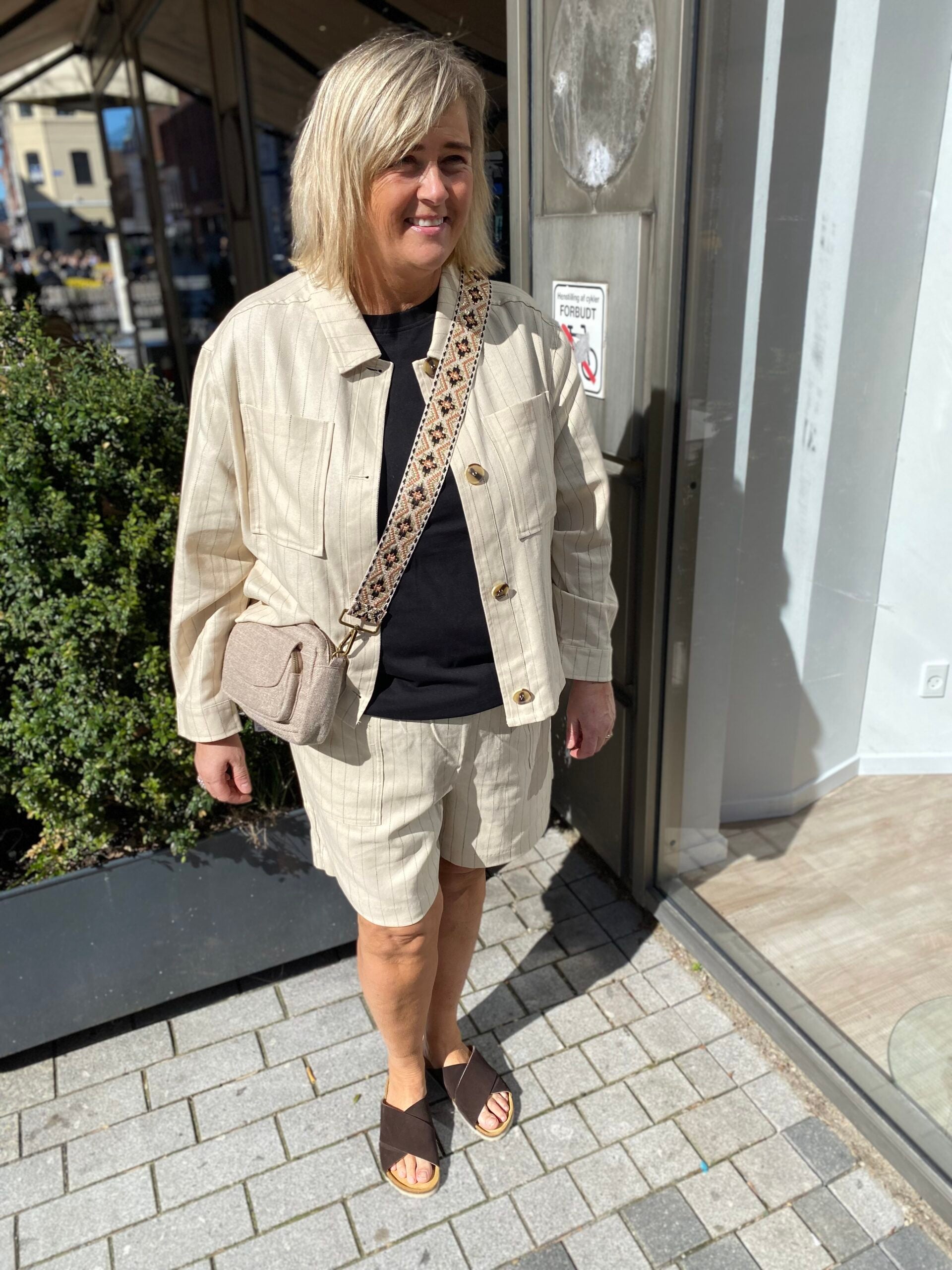 Janni med beige skuldertake og beige shorts med tynde sorte striber.