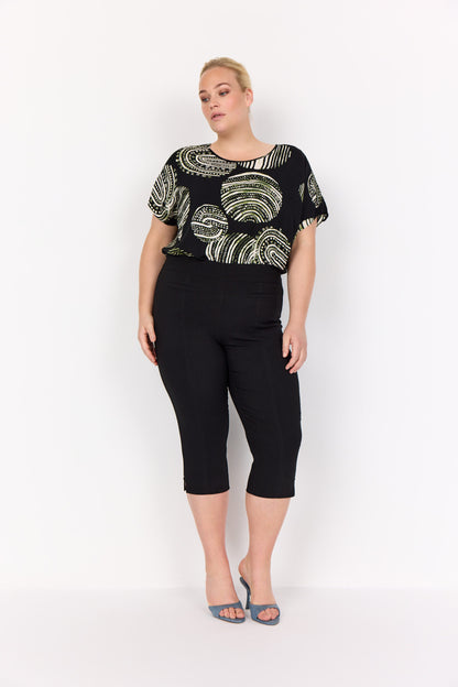 model med sorte bukser og mønstret t-shirt med korte ærmer og rund hals. Wasabi WA-MEDINE 1 T-shirt Black Combi