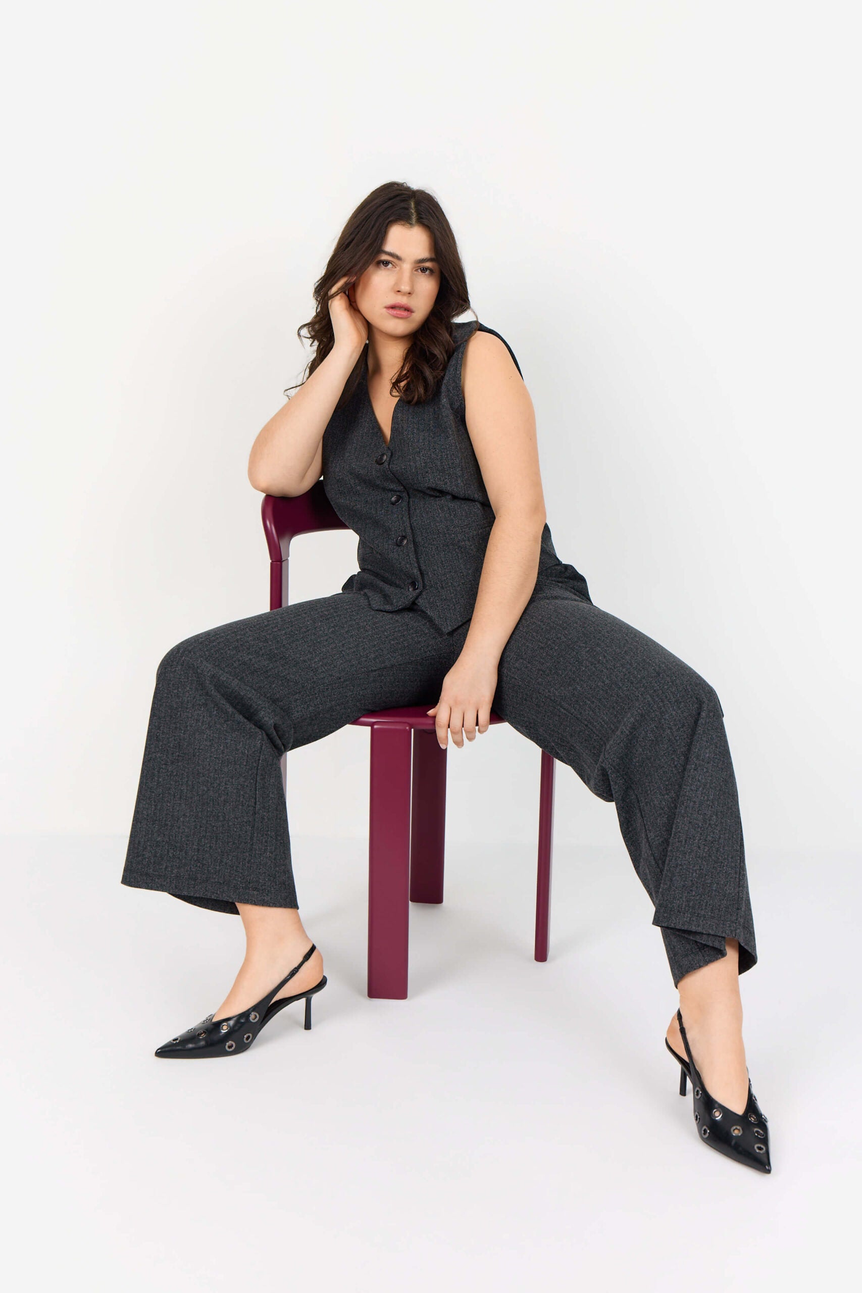 model på stol med mørkegrå bukser med diskrete striber. Wasabi WA-NOIDA 3 Bukser Dark Earth Melange Comb