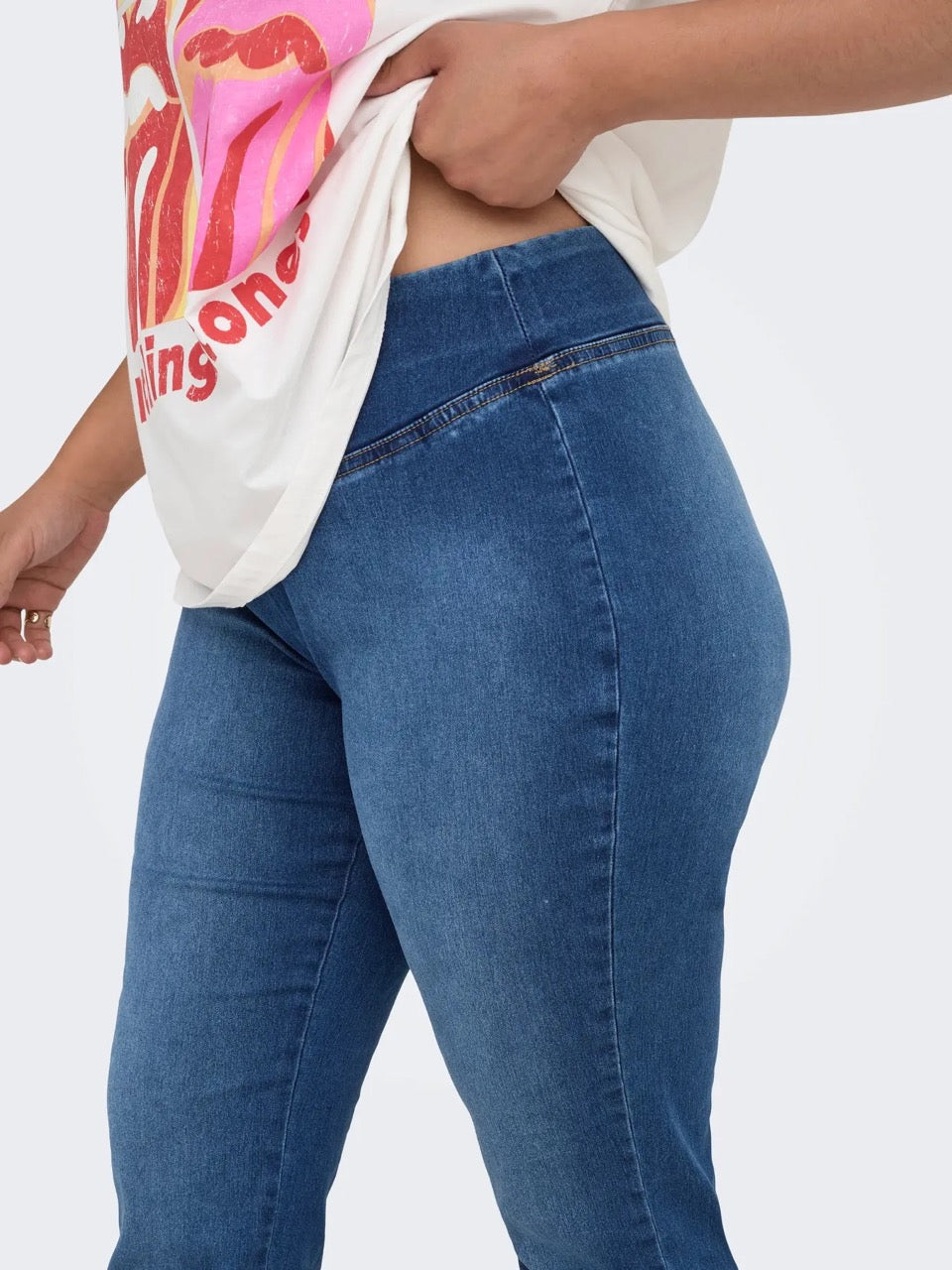 siden af model med blå jeans med bred elastik i taljen. ONLY Carmakoma CARROYAL Flared Legging Medium Blue Denim