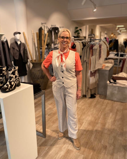 Lene med coralfarvet t-shirt, Freequent FQNANNI-WAISTCOAT og stribet beige hørbukser