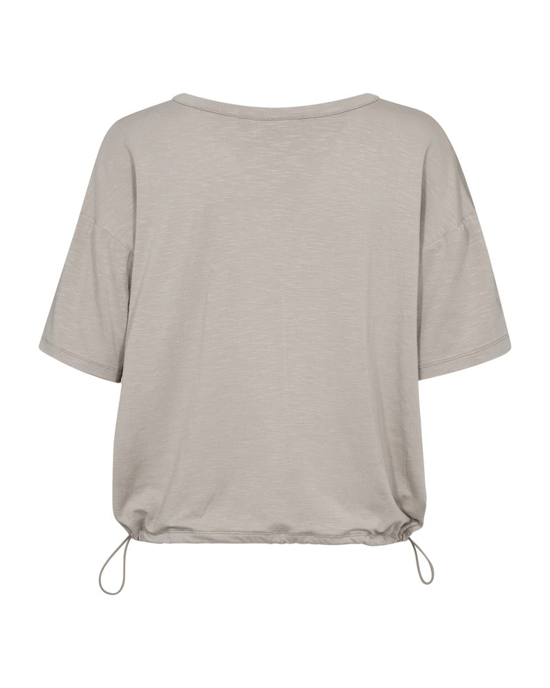 ryggen af kortærmet beige bluse med justerbar snøre i bunden